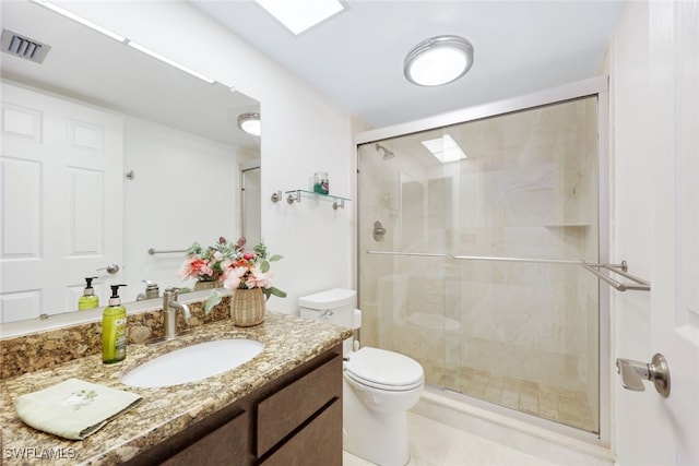 bathroom with toilet, vanity, and a shower with shower door