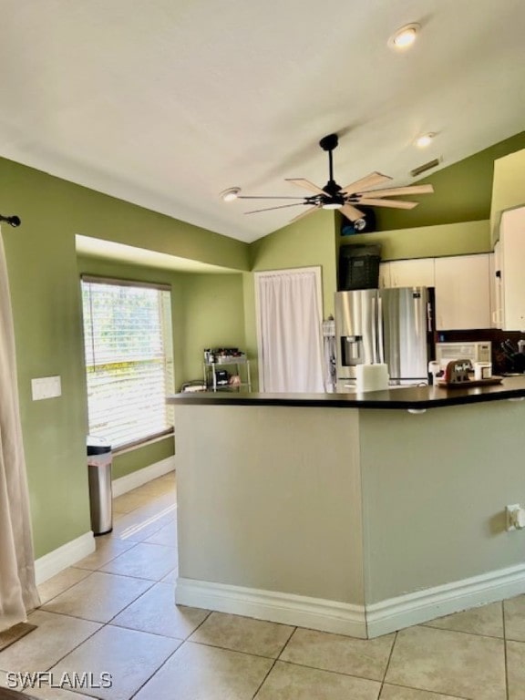 kitchen featuring light tile patterned flooring, white cabinetry, stainless steel refrigerator with ice dispenser, ceiling fan, and vaulted ceiling