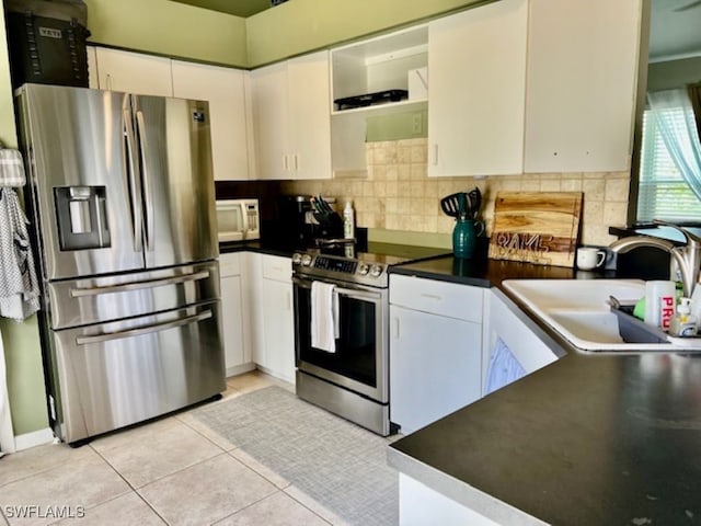 kitchen featuring appliances with stainless steel finishes, sink, light tile patterned floors, and white cabinets