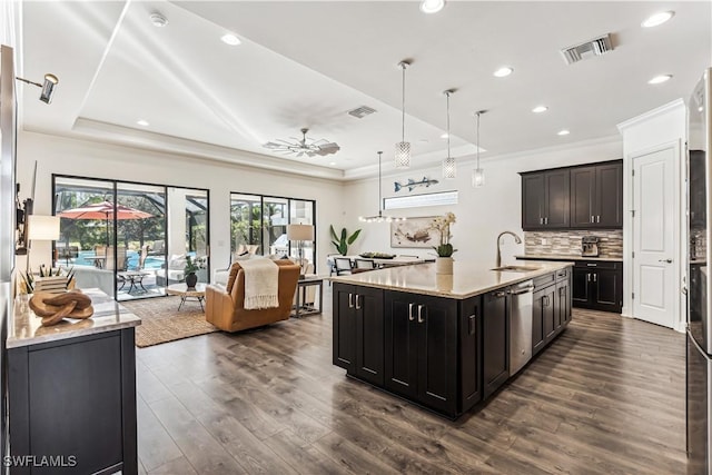 kitchen featuring a tray ceiling, sink, pendant lighting, a center island with sink, and dark hardwood / wood-style floors