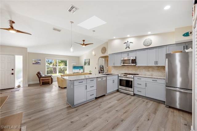 kitchen with sink, gray cabinetry, stainless steel appliances, light stone countertops, and kitchen peninsula