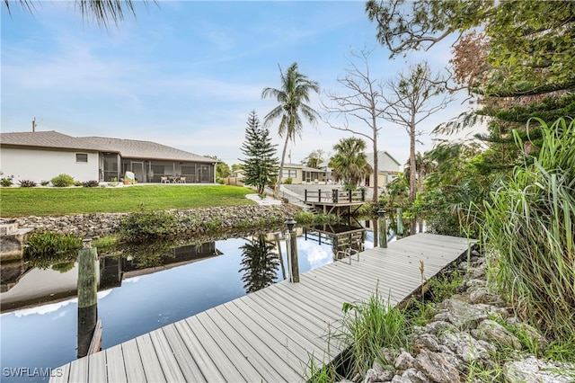 view of dock with a water view and a lawn