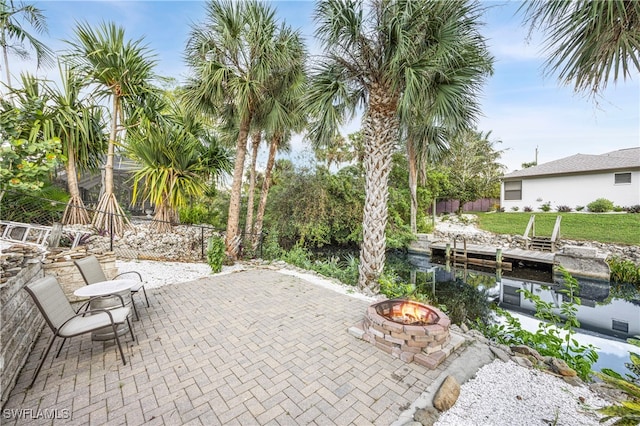 view of patio with a water view, a boat dock, and a fire pit