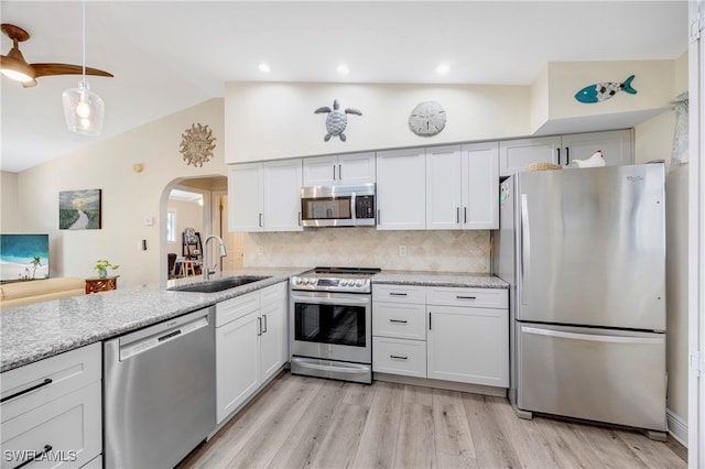 kitchen featuring vaulted ceiling, appliances with stainless steel finishes, sink, and white cabinets