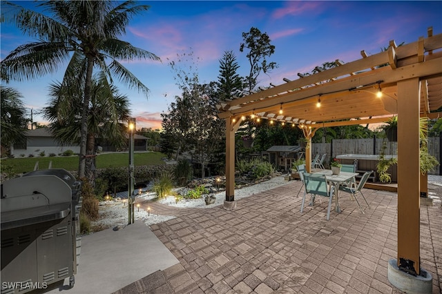 patio terrace at dusk with a pergola and a hot tub