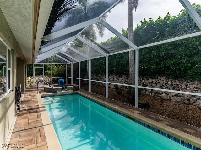 view of swimming pool with a patio, glass enclosure, and a hot tub