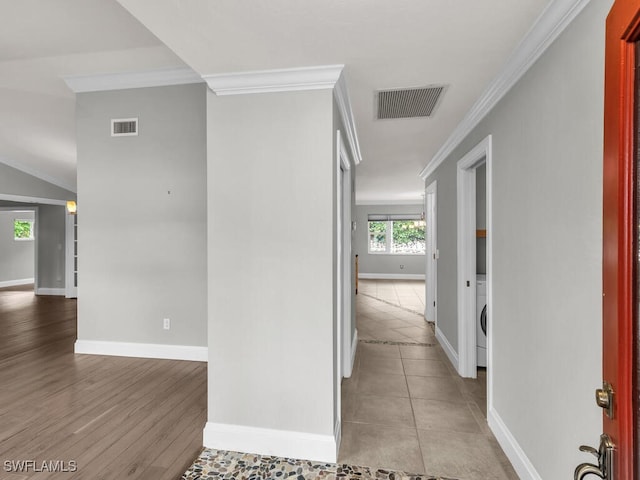 hall with washer / dryer, ornamental molding, and light hardwood / wood-style flooring