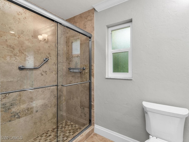 bathroom featuring a shower with shower door and toilet