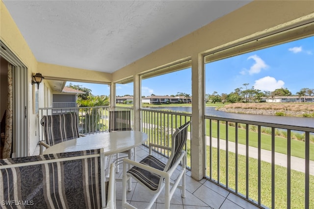 sunroom featuring a water view