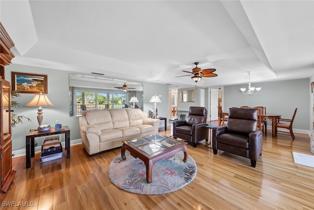 living room with ceiling fan with notable chandelier and light wood-type flooring