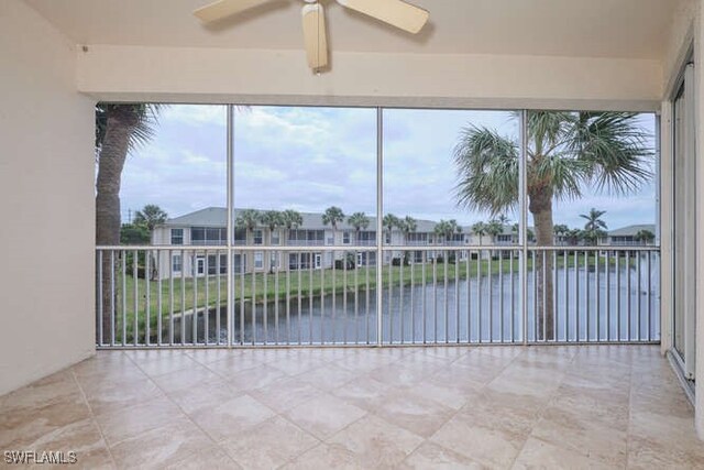 unfurnished sunroom with ceiling fan and a water view