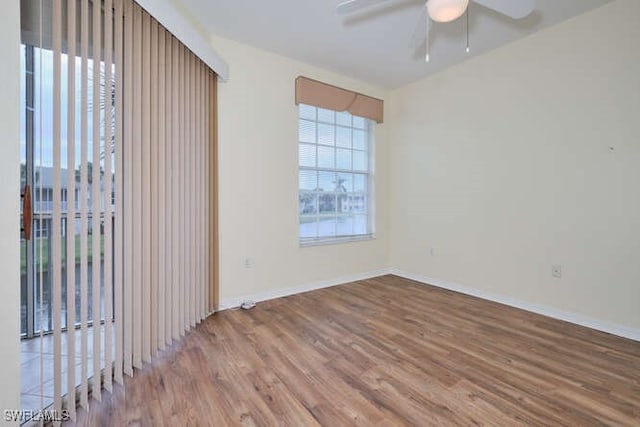 unfurnished room with wood finished floors, a ceiling fan, and baseboards