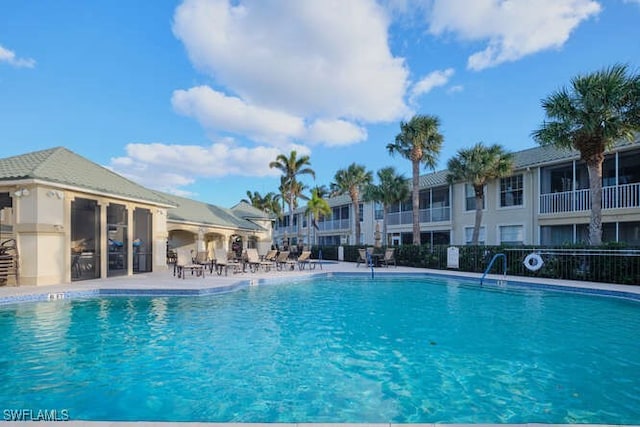 community pool with a patio area and fence