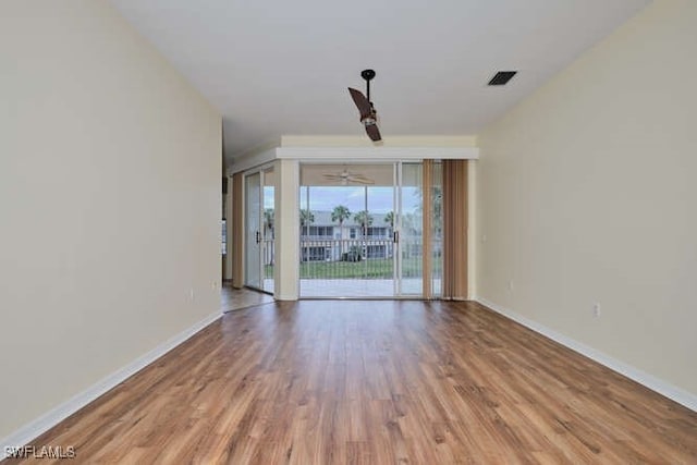 spare room featuring wood finished floors, visible vents, and baseboards