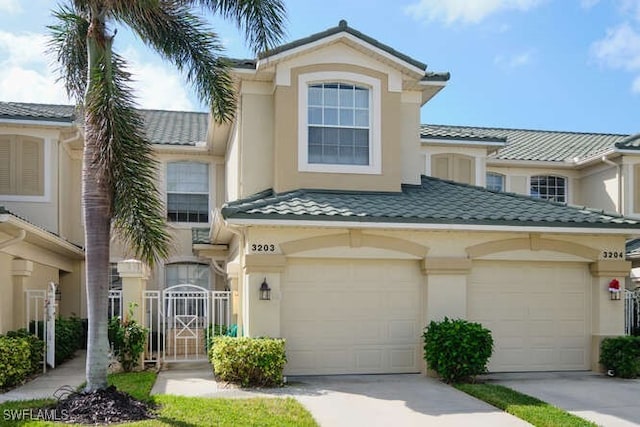 view of front of property with driveway, a tile roof, a gate, and stucco siding