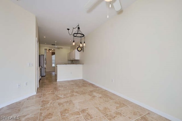 unfurnished living room featuring ceiling fan and baseboards