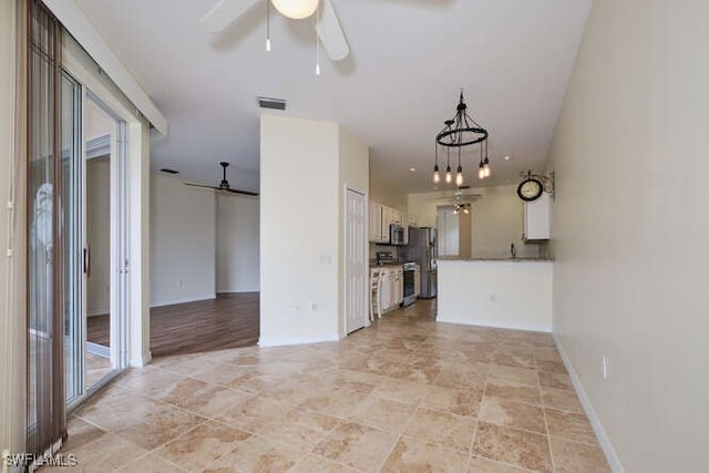 unfurnished living room featuring ceiling fan with notable chandelier