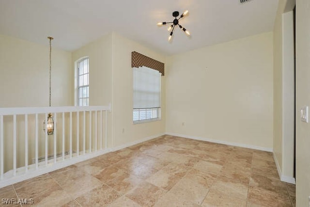 spare room with a chandelier, visible vents, and baseboards