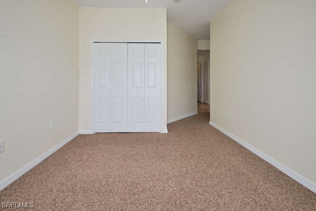 unfurnished bedroom with carpet floors, a closet, and baseboards