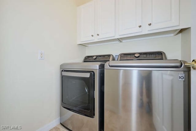 washroom with cabinets and washing machine and clothes dryer