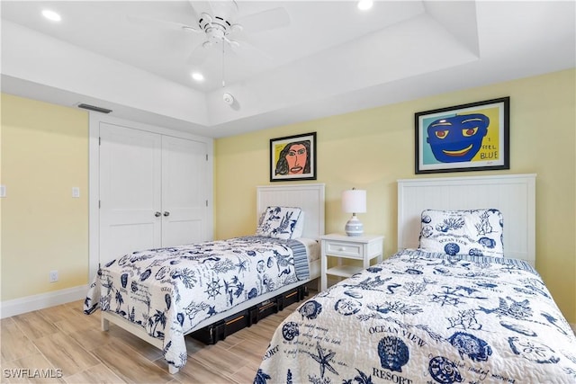 bedroom featuring ceiling fan, a tray ceiling, and a closet