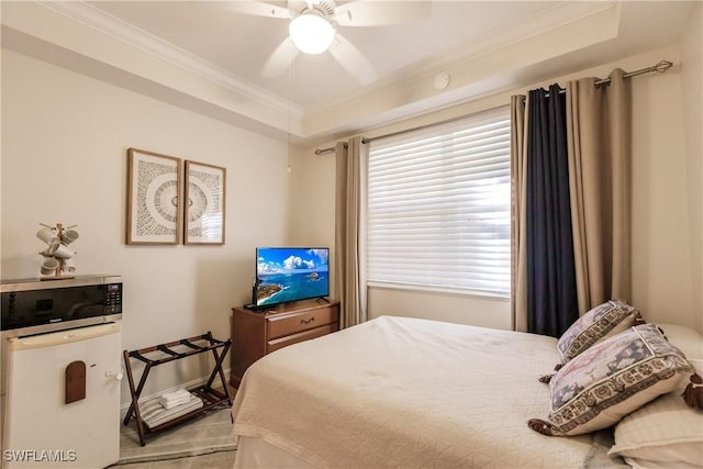 bedroom featuring ceiling fan, a raised ceiling, and crown molding