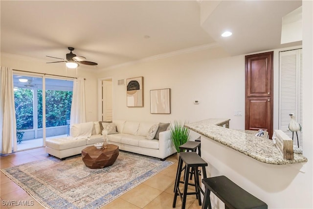 living room with ceiling fan, light tile patterned floors, and ornamental molding