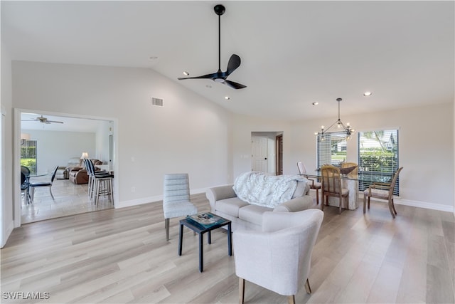 living room featuring ceiling fan with notable chandelier, vaulted ceiling, and light wood-type flooring