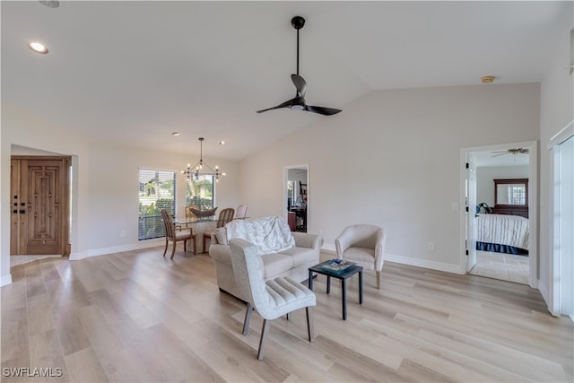 living room featuring ceiling fan with notable chandelier, vaulted ceiling, and light wood-type flooring