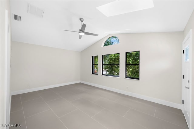 tiled spare room featuring vaulted ceiling with skylight and ceiling fan