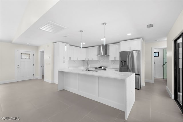 kitchen with sink, wall chimney exhaust hood, light stone counters, white cabinetry, and stainless steel appliances