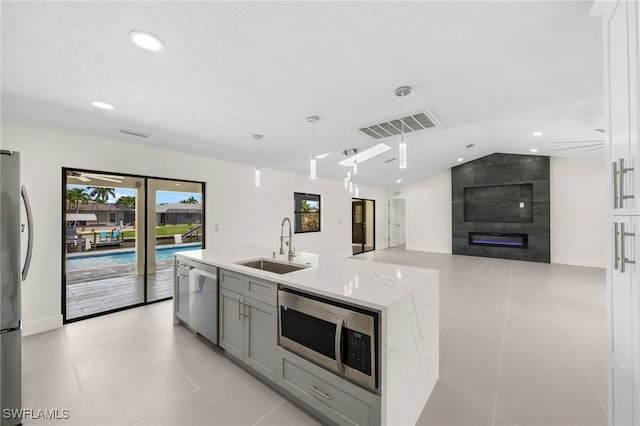 kitchen with sink, light stone counters, decorative light fixtures, light tile patterned flooring, and appliances with stainless steel finishes