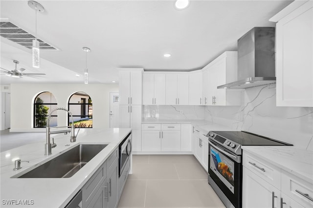 kitchen featuring pendant lighting, white cabinets, sink, wall chimney exhaust hood, and appliances with stainless steel finishes