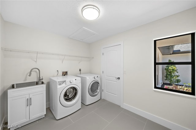 laundry area with cabinets, light tile patterned floors, washer and clothes dryer, and sink