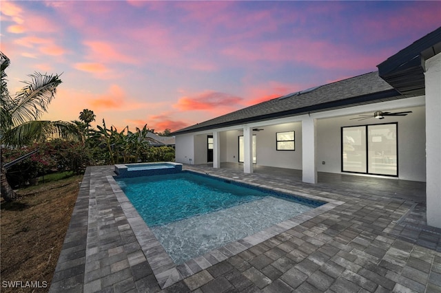 pool at dusk featuring an in ground hot tub, a patio, and ceiling fan