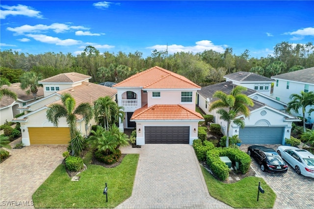 mediterranean / spanish-style home with a garage, a balcony, and a front lawn