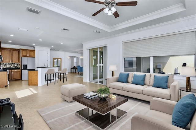 living room featuring light tile patterned floors, a raised ceiling, ceiling fan, and crown molding