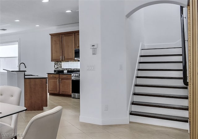 kitchen with sink, stainless steel appliances, backsplash, crown molding, and light tile patterned floors