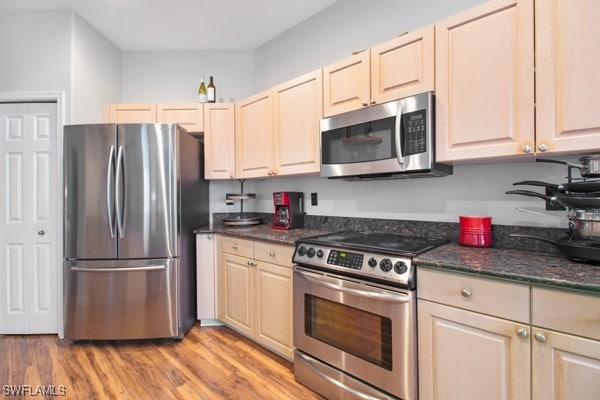 kitchen with dark stone countertops, light wood-type flooring, and stainless steel appliances