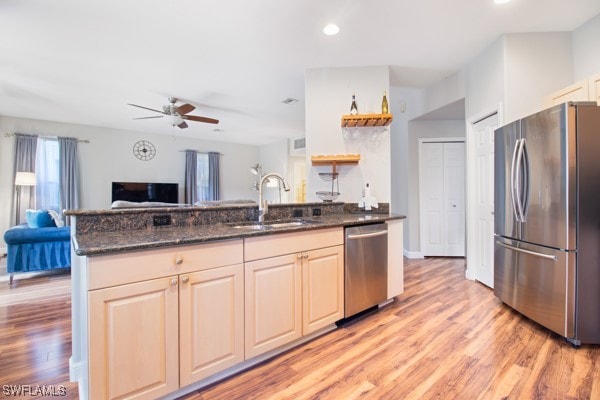 kitchen featuring dark stone counters, sink, ceiling fan, light hardwood / wood-style floors, and stainless steel appliances