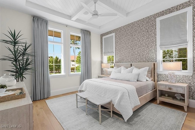 bedroom featuring wallpapered walls, light wood-type flooring, coffered ceiling, baseboards, and beam ceiling