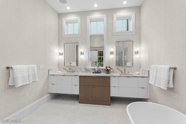 bathroom with a soaking tub, vanity, baseboards, and recessed lighting