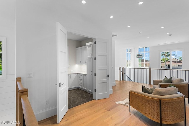 living area featuring light wood-style floors, an upstairs landing, recessed lighting, and baseboards