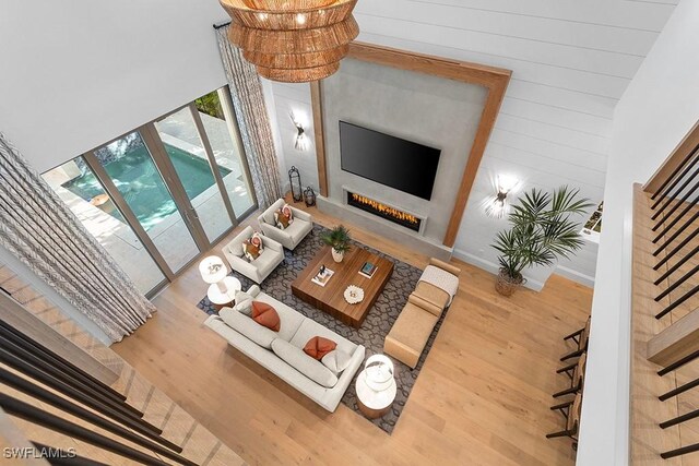 living room with wood finished floors, a warm lit fireplace, and wood walls