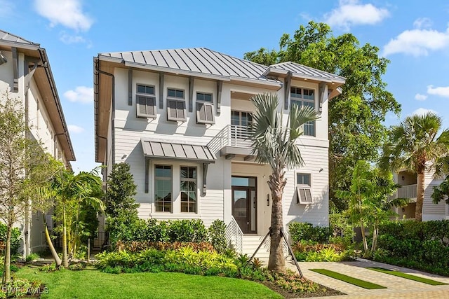 view of property with a standing seam roof, metal roof, and a front lawn