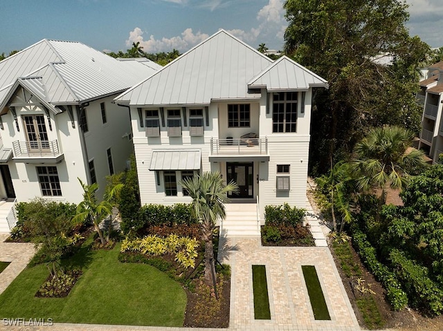 view of front of home with a standing seam roof, metal roof, and a balcony