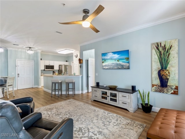 living room with light hardwood / wood-style floors, ceiling fan, and ornamental molding