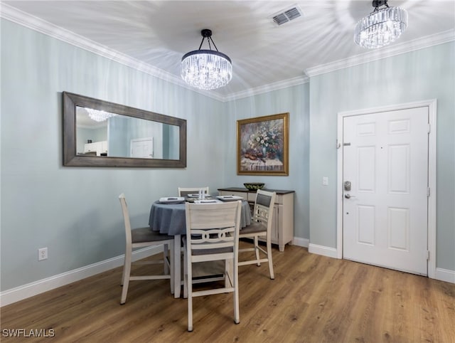 dining room featuring hardwood / wood-style floors, crown molding, and an inviting chandelier