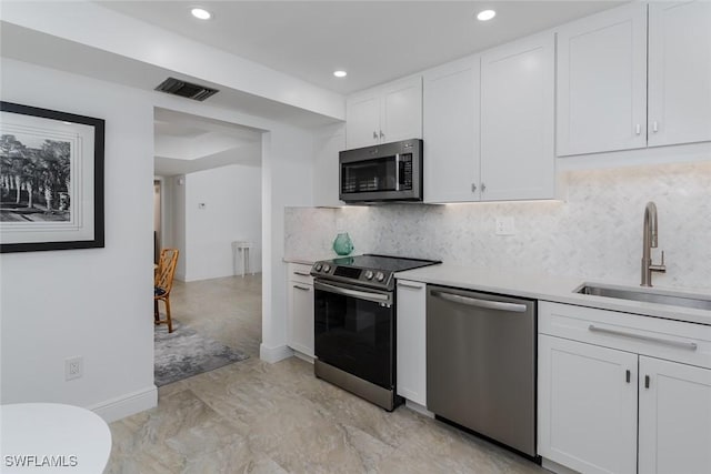 413 Augusta Blvd Unit 205, Naples, FL 34113 - kitchen with appliances with stainless steel finishes, a sink, white cabinetry, light countertops, and decorative backsplash
