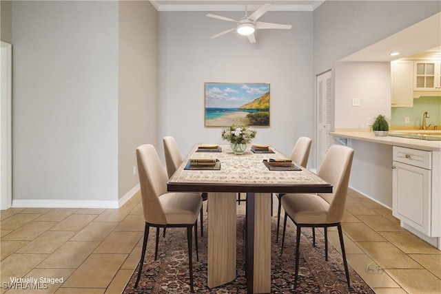 tiled dining room with a high ceiling, ceiling fan, and ornamental molding